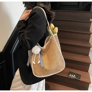 Détail du sac cabas en paille tissée avec garniture en cuir blanc et ruban à pompon