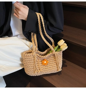 Detail of crochet tote bag featuring beige knit texture and bright orange flower accent