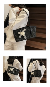 Detail of black faux snakeskin tote bag featuring a decorative pearl bow charm pendant