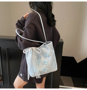 Dettaglio del ricamo a farfalla 3D e fiocco di pizzo su una borsa tote celeste