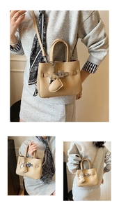 Detail of lychee textured leather tote with silver metal twist lock and heart charm