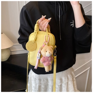 Detail of yellow lychee pattern phone bag with a cute bear charm and smiley accessory