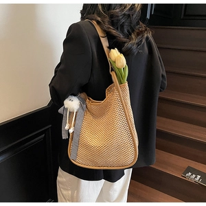Détail du sac cabas en paille évidée avec bordure en cuir marron et breloque peluche
