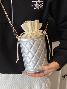 Silver quilted bucket bag with gold chain strap and drawstring closure shown on model