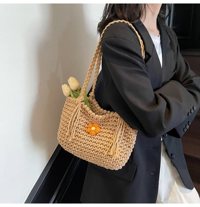 Close-up of beige chunky knit tote bag featuring 3D crochet flower and side tassels