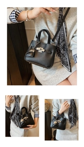 Detail showing black lychee leather texture and silver metal twist lock on bucket bag