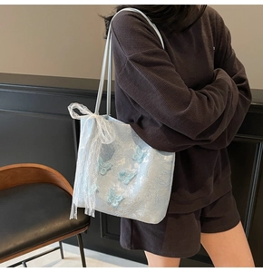 Dettaglio della borsa tote azzurra con farfalle 3D e fiocco in pizzo sulla tracolla