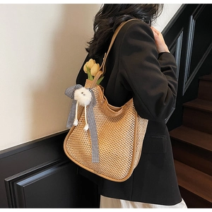 Détail du sac cabas en paille tressée avec pendentif ours et nœud en ruban à carreaux