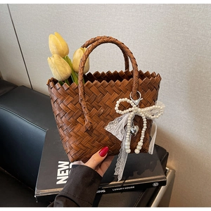 Détail d'un sac cabas en paille tressée marron avec charm perle et décor de tulipe