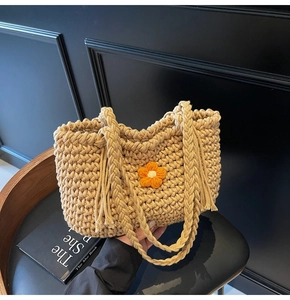Detailed texture of hand-woven beige tote bag with knit flower and braided handles