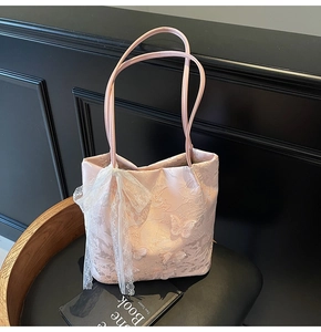 Dettaglio della borsa tote in pizzo rosa con ricamo a farfalla e fiocco di nastro elegante