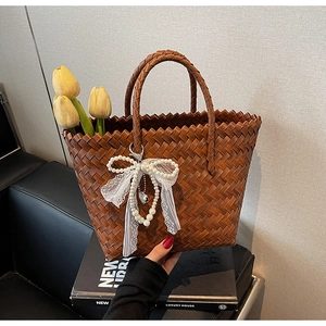 Détail d'un sac panier tressé avec nœud en dentelle élégant et pendentif en perle