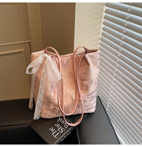 Dettaglio della borsa tote rosa chiaro con ricamo floreale in pizzo e fiocco bianco