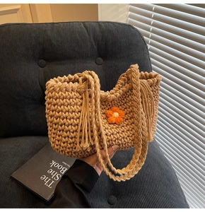 Detail of hand-woven khaki tote bag featuring a 3D floral accent and tassel handle