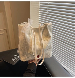 Dettaglio della borsa tote in pizzo bianco con ricamo a farfalla e fiocco elegante