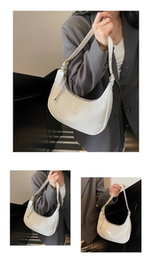 Detailed close-up of white patent leather crescent bag with golden buckle and logo