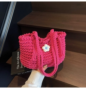 Detail of rose red woven tote bag featuring a 3D blue flower and thick crochet texture