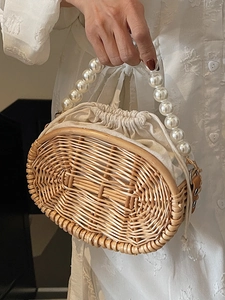 Handwoven straw handbag with pearl handle and canvas drawstring for beach vacations