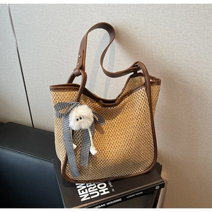 Détail du sac cabas en paille avec bordure en cuir marron et pendentif ours