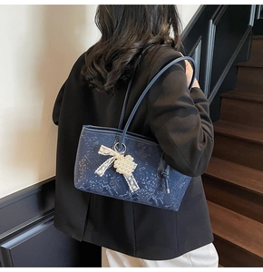 Détail du sac cabas bleu marine en cuir serpent avec pendentif perle et dentelle