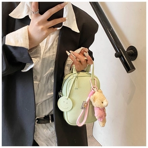 Mint green pebble leather crossbody bag with cute bear charm shown on a model
