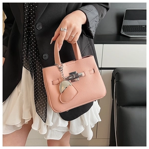 Detailed close-up of pink lychee grain leather handbag with silver buckle and heart charm