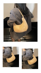 Detail view of a beige glossy patent leather hobo bag showing the elegant saddle shape