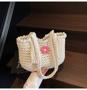 Detailed close-up of cream woven tote bag with 3D crochet flowers on rustic wood