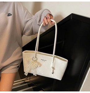 Détail du sac à bandoulière blanc texture serpent avec charms perle et nœud dentelle