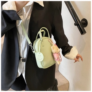 Detail of mint green crossbody phone bag with bear charm and litchi grain texture