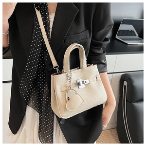 Detail of lychee textured leather cream bucket bag with silver lock and heart charm