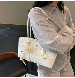 Détail du cabas blanc avec motif diamant, breloque cœur en perles et nœud en dentelle