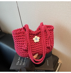 Close-up of handmade pink crochet tote bag featuring a 3D floral accent on a book