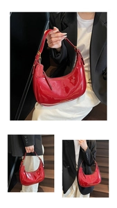 Close-up of shiny red patent leather hobo bag with gold hardware and smooth curved texture