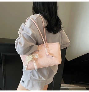 Détail du sac rose texture serpent avec pendentif cœur en perle et nœud en dentelle
