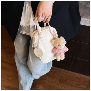 Detail of cream white lychee texture mini bag with pink bear and smiley face charm