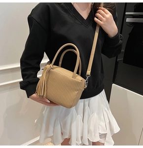 Détail de la texture du cuir et du gland à franges sur le sac à main marron
