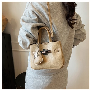 Close-up of beige lychee grain leather bucket bag featuring silver lock and heart charm