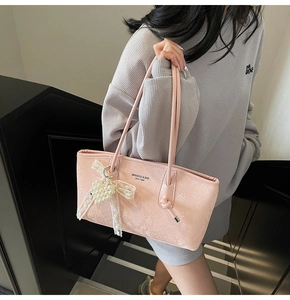 Détail du sac cabas rose motif python avec pendentif nœud perlé sur un escalier