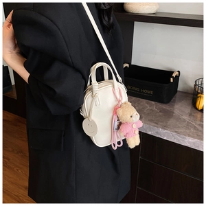 Detail of white lychee-grain faux leather crossbody bag with cute pink bear charm