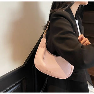 Detail of light pink patent leather shoulder bag with golden hardware and logo tag