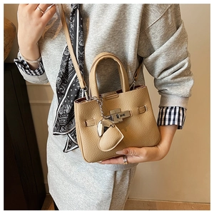 Close-up of khaki lychee grain leather bucket bag with silver metal lock and heart charm