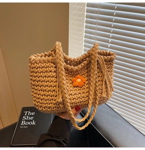 Close-up of hand-woven knit tote bag featuring a bright orange flower and tassel details