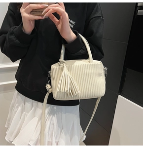 Détail du sac bandoulière blanc cassé avec texture plissée et grand pompon décoratif