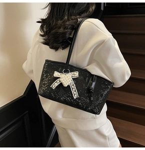 Detail of black snake-embossed shoulder bag with white lace bow and pearl charms