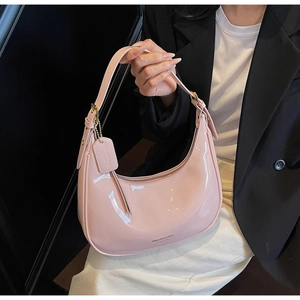 Detail of light pink patent leather hobo bag showing glossy texture and gold buckle