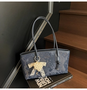 Détail du sac cabas bleu marine à motif serpent avec breloque cœur perlé et nœud