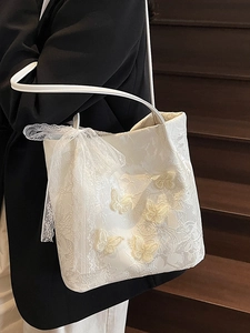 Elegante borsa tote bianco sporco con farfalle 3D e trama in pizzo indossata da modella