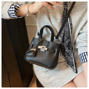 Detailed view of black lychee grain leather bucket bag with silver turn-lock and strap