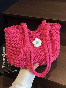 Handmade magenta macrame woven basket bag with white flower detail and fringe handle